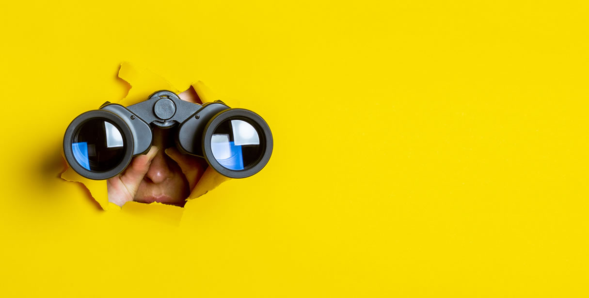 Binoculars breaking through yellow paper