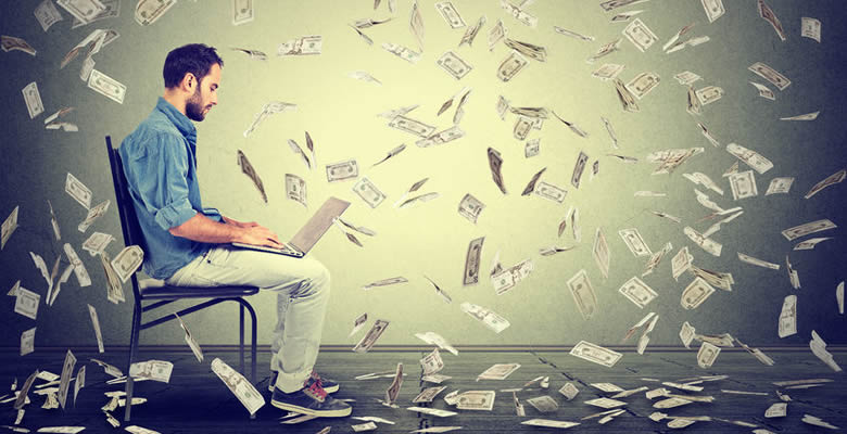 Man working on laptop with money raining down